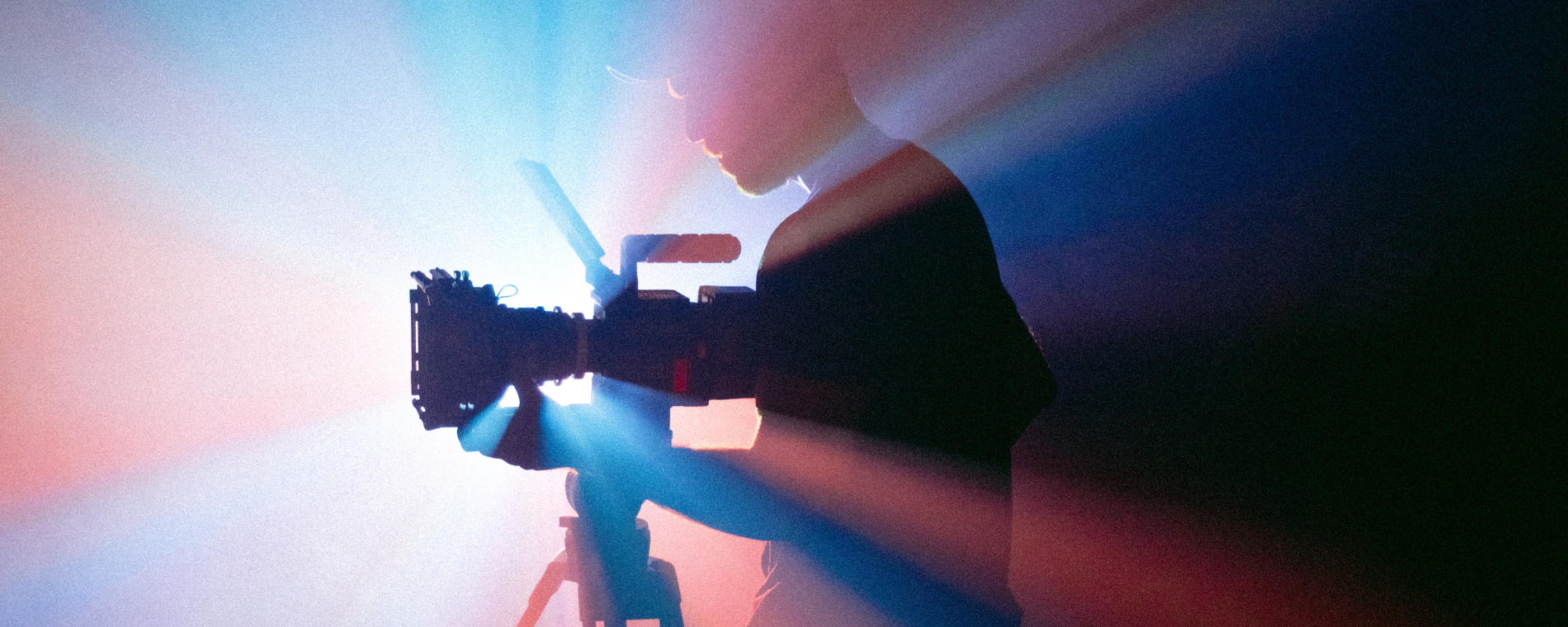 man holding camera silhouetted with pink and blue lights