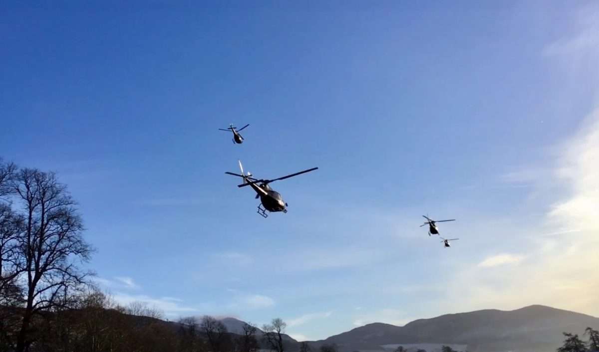 four helicopters flying over scotland mountains
