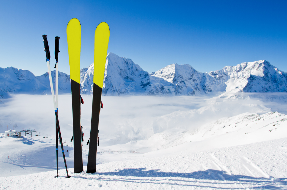 winter travel by private jet for ski season. Skis standing up in snow with snowy mountain in background