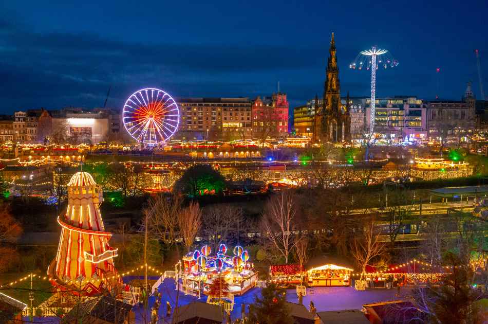 Cityscape of Edinburgh at Christmas. Christmas market stalls full of lights, multicoloured amusement park rides and ferris wheel.