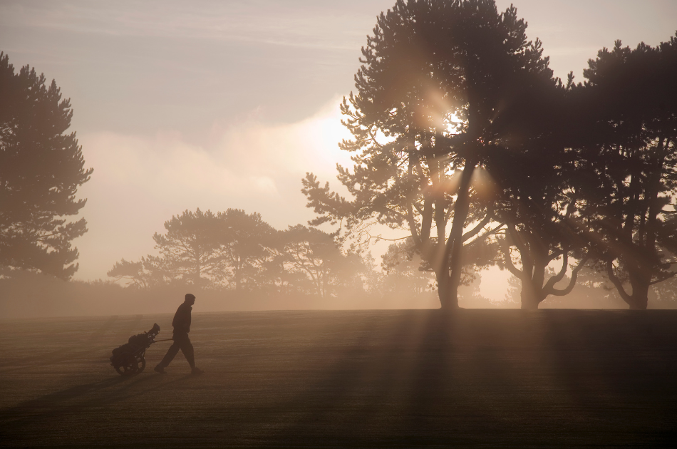 golfer walking on golf course at sunrise