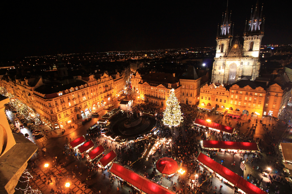 European Christmas market filling the town square in Prague with red stalls and a big Christmas tree in the centre.