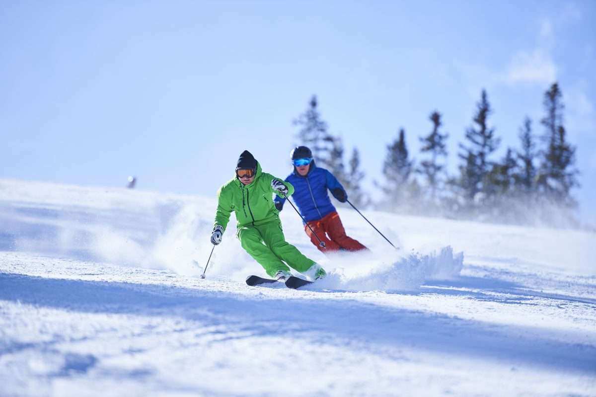 Two men skiing down snow covered ski slope in Aspen, Colorado, USA