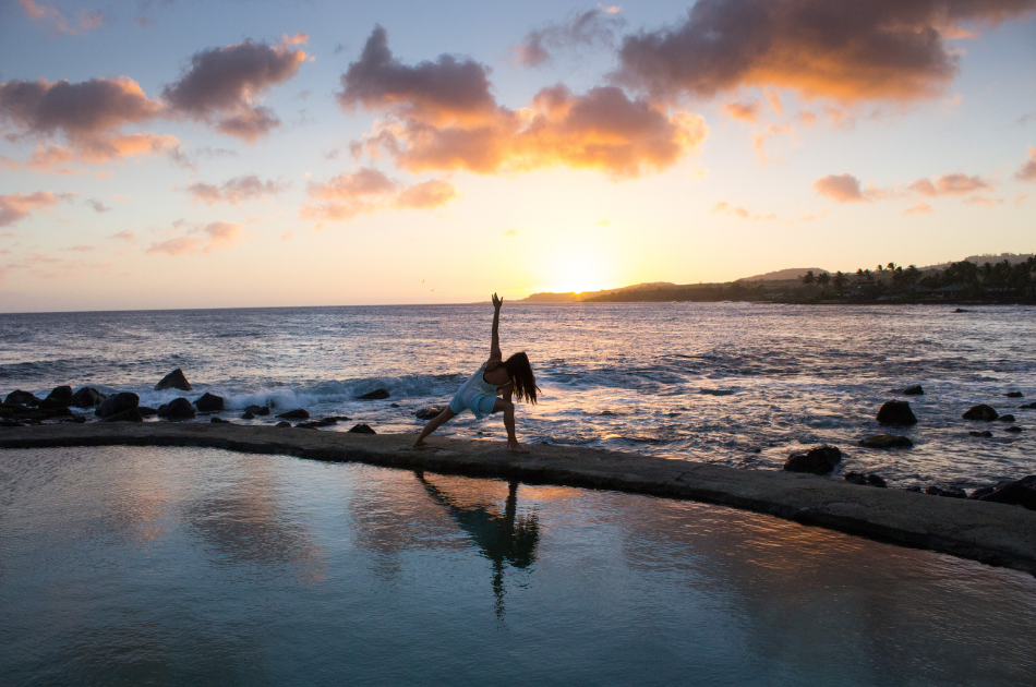 Woman practicing wellness yoga at sunset on the beach
